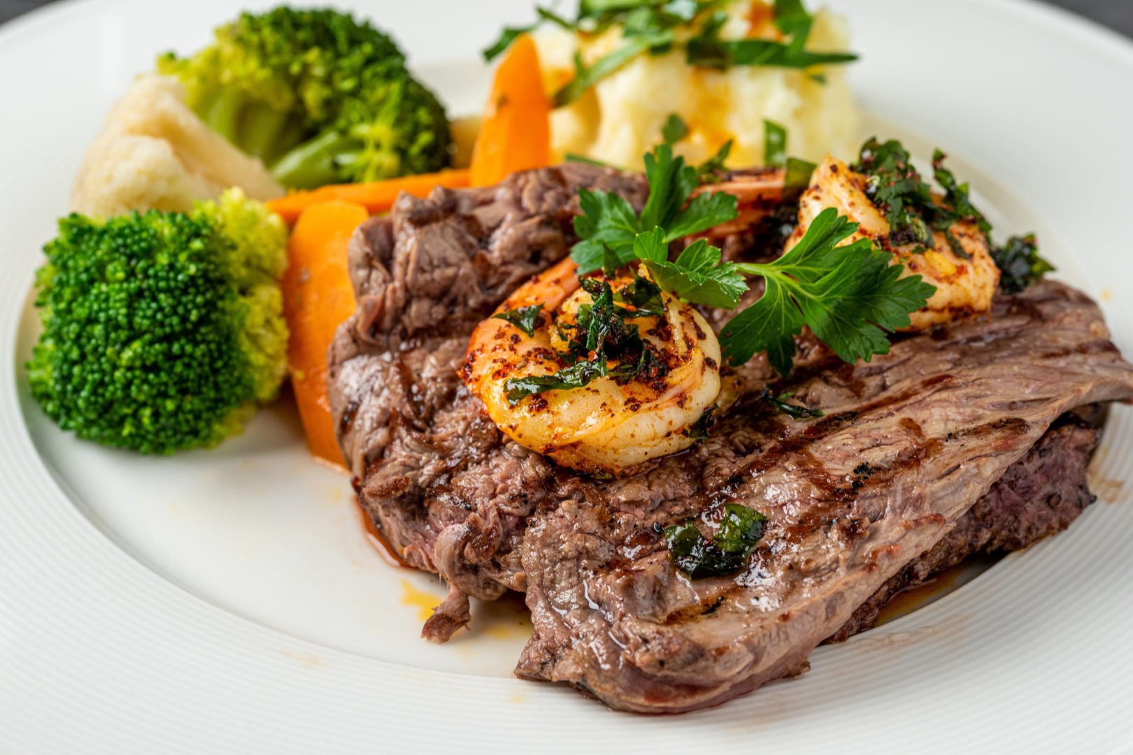 Delicious juicy grilled steak and shrimp with grilled broccoli and cauliflower. Surf and Turf style.